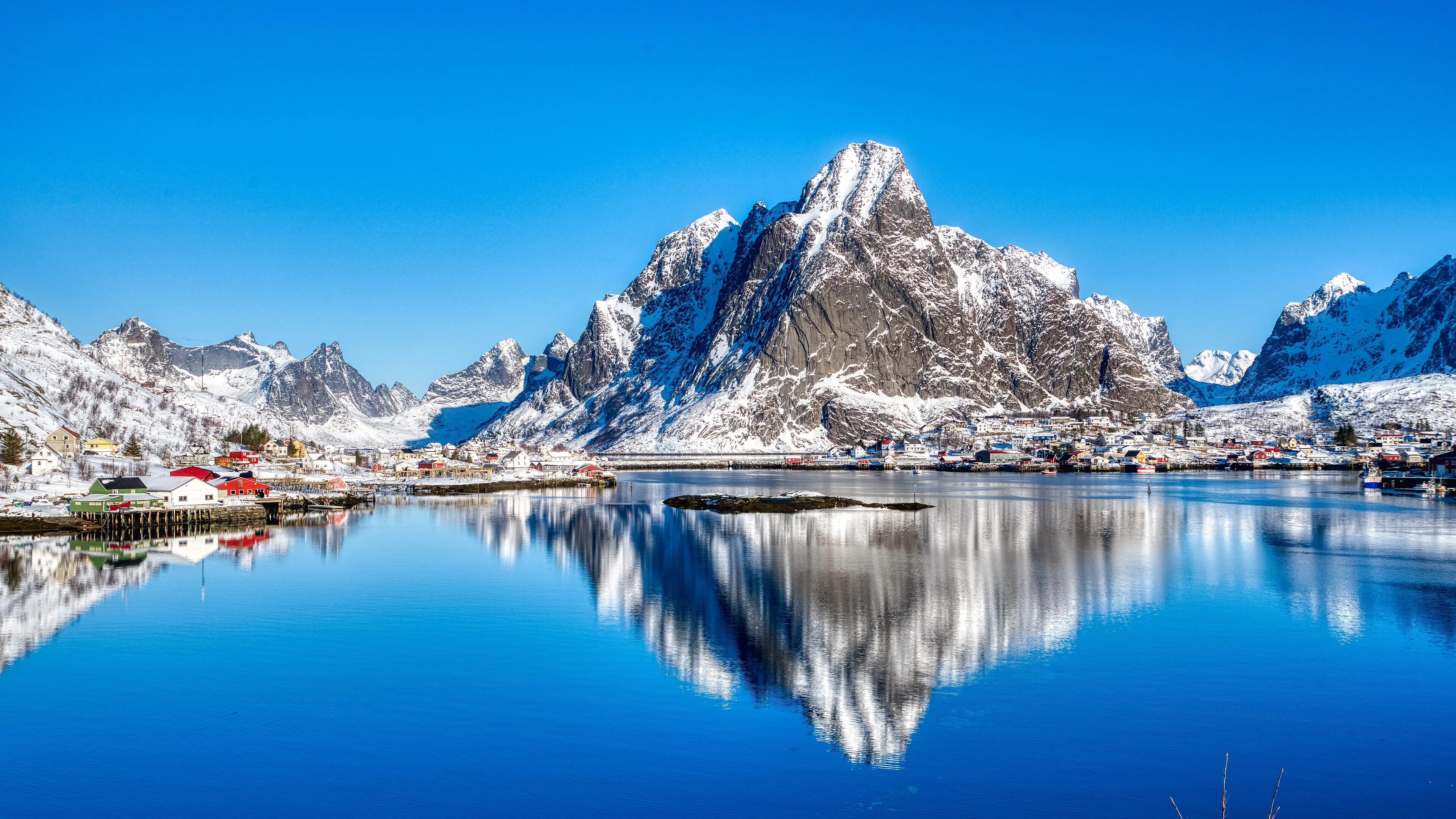 Red fishing cabins below granite peaks at Reine in the Lofoten islands, Norway